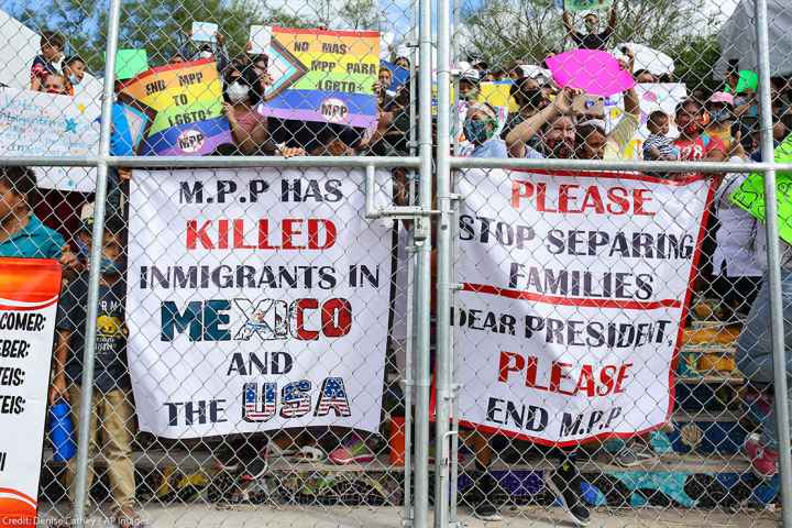 People press signs against a closed gate to the migrant encampment, asking then President Donald Trump to end the Migrant Protection Protocols during a rally at the encampment in Matamoros, Tamaulipas, Mexico on October 25, 2020.