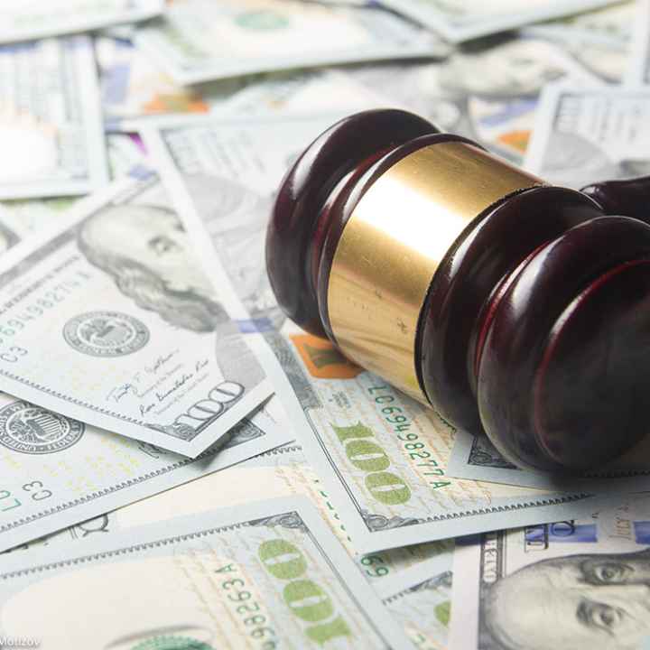 A judges' gavel on a U.S. dollar cash background, top view, close-up.