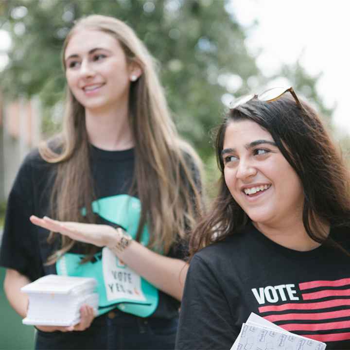 Two smiling canvassers carrying voting information.