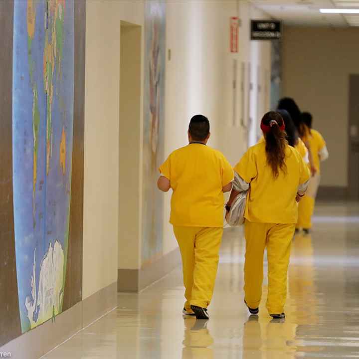 Detainees walk past a map of the world in a hallway of a U.S. Immigration and Customs Enforcement (ICE) detention facility.