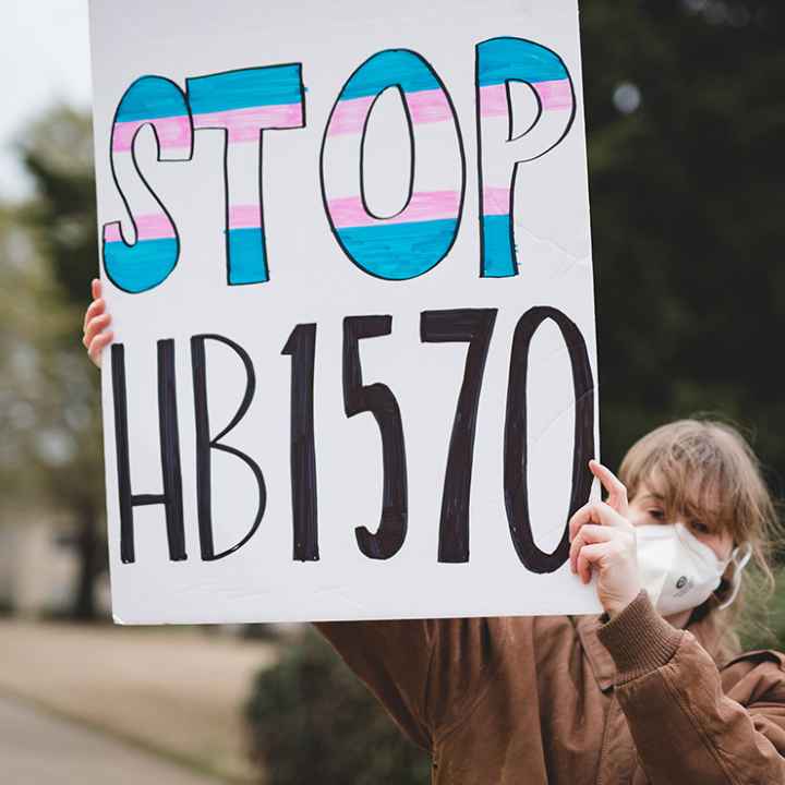 A demonstrator holding a sign with the text "Stop HB1570."